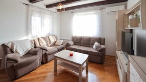 A living room with two sofas, a coffee table, wooden beams on the ceiling, and a TV stand. - Country Villa With Pool and Garden (Benkovac)
