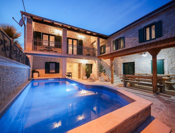 A courtyard with a swimming pool, stone buildings, and outdoor seating. - Country Villa With Pool and Garden (Benkovac)