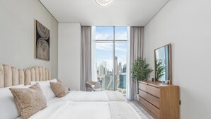Una camera da letto moderna con vista sulla città, un letto grande, una cassettiera e una sedia.