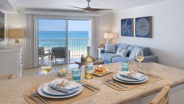 Un comedor con vista al océano, un ventilador de techo y un balcón con sofá y mesa.