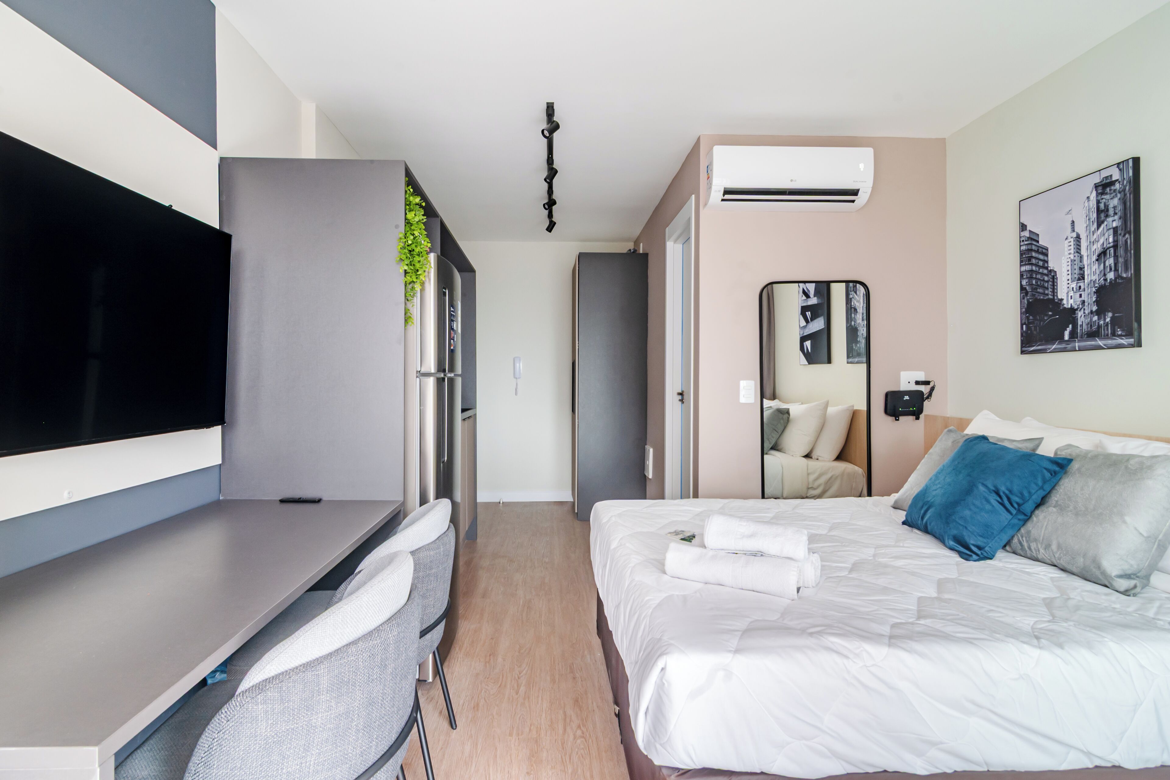 Une chambre d’hôtel moderne équipée d’un lit, d’un bureau, d’une chaise, d’un climatiseur et d’un miroir.