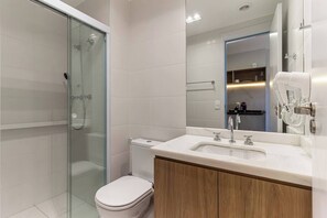 A modern bathroom with a glass shower enclosure, a toilet, and a vanity with a mirror. - 360 The Collection Madalena (São Paulo)