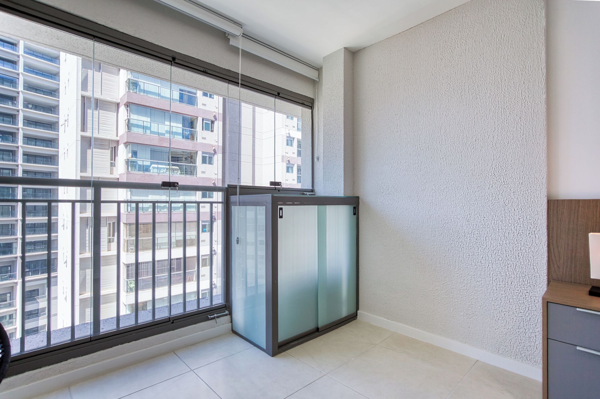 Un appartement moderne doté d’un grand balcon, d’une porte coulissante et offrant une vue sur d’autres immeubles.