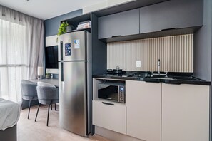 A modern kitchen with a built-in microwave, a stainless steel refrigerator, and a gas stove. - 360 The Collection Madalena (São Paulo)