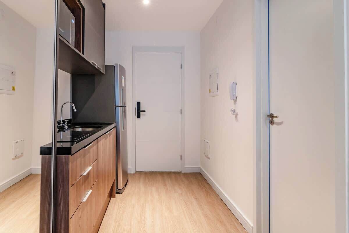 A compact kitchen with a refrigerator, sink, and wooden cabinets.