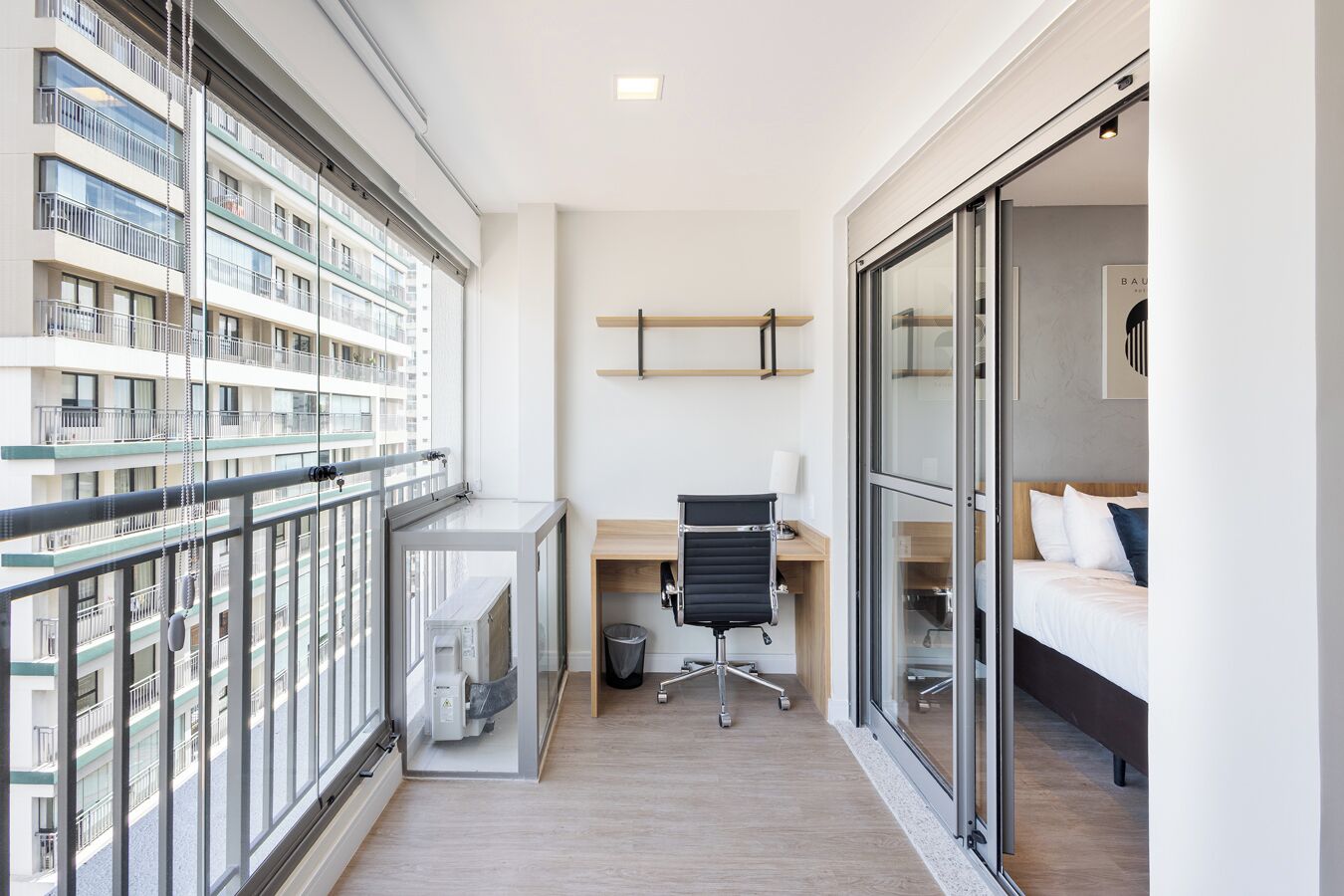 Een modern appartement met een balkon, een kantoorhoekje en een slaapkamer.