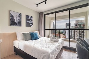 A hotel room with a large bed, a city view balcony, and two framed pictures on the wall. - 360 The Collection Madalena (São Paulo)