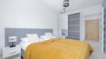 Une chambre à coucher moderne, avec un lit, des tables de chevet, une armoire et une porte.