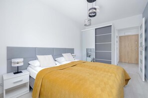 Een moderne slaapkamer met een bed, nachtkastjes, een kledingkast en een deur.