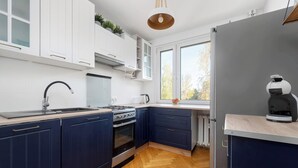 A modern kitchen with white and dark blue cabinets, a stainless steel stove, and a built-in oven. - Spacious Apartment in Wroclaw | Air Conditioning and Balcony (Wrocław)