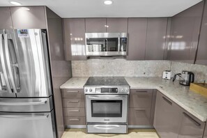 A modern kitchen with stainless steel appliances, a microwave, and a built-in oven. - Bay View Condo | Work-Ready & Balcony (Miami)