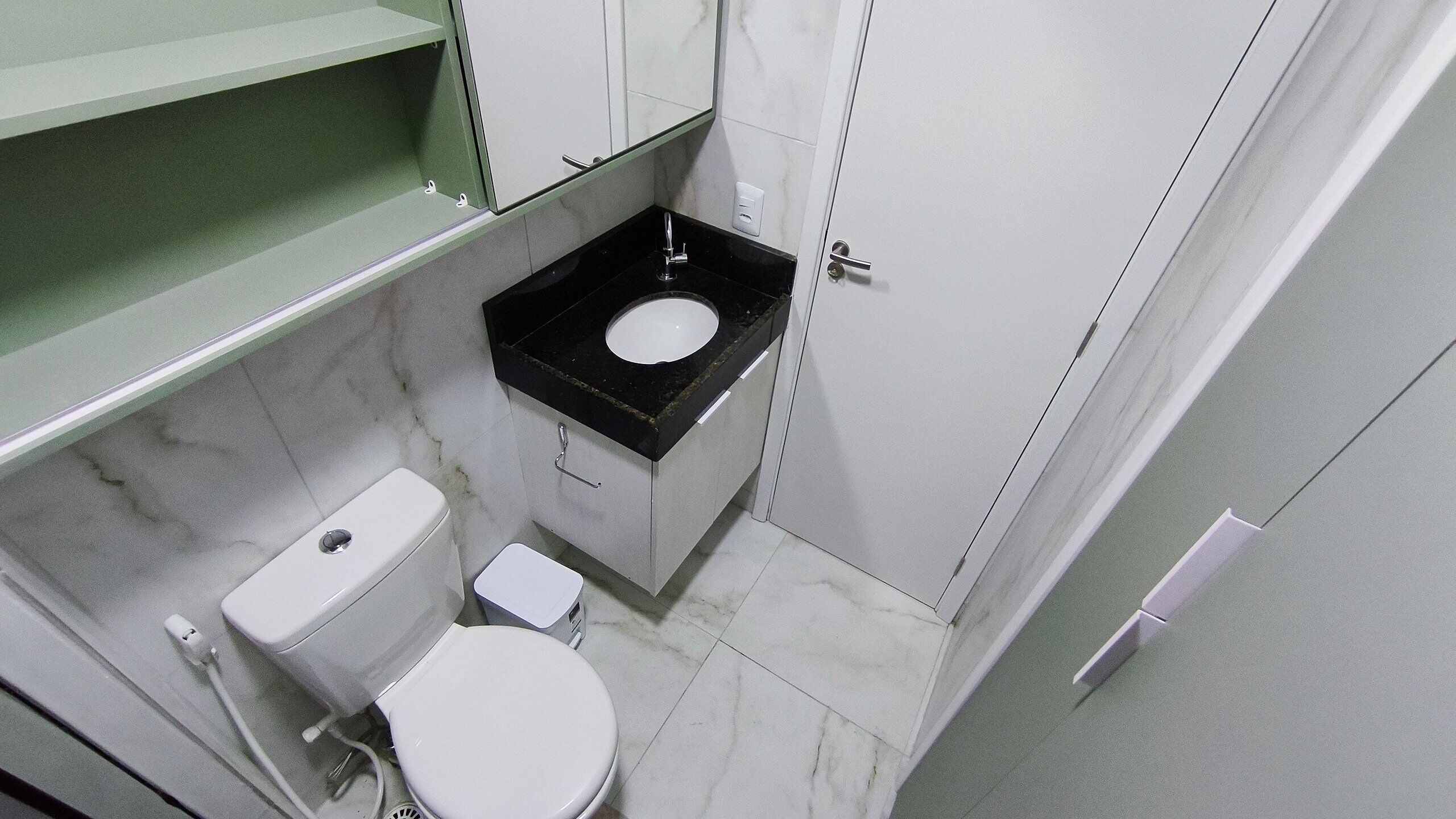 A small bathroom with a toilet, sink, and mirror.