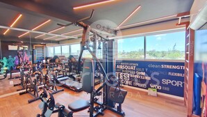 Une salle de sport équipée de divers appareils d’exercice, dotée de grandes fenêtres et ornée de citations motivantes sur les murs.