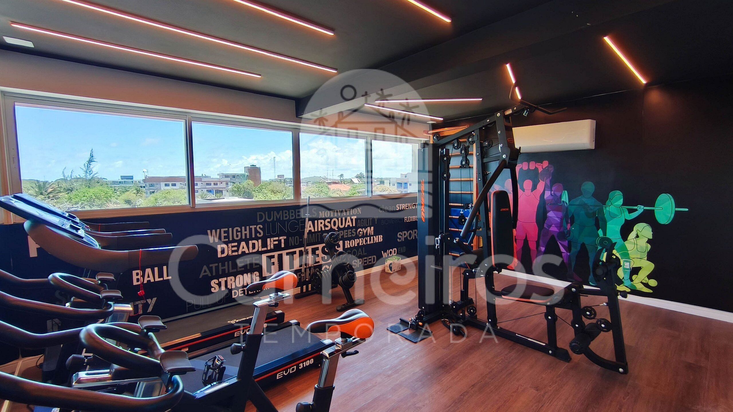 Une salle de sport équipée de matériel d’exercice, agrémentée de décorations murales inspirantes et dotée de grandes fenêtres.