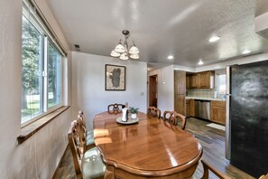 A dining room with a wooden table, chairs, a chandelier, and a view of the kitchen. - 853p Lakeside Beach 4 Bedroom Home (South Lake Tahoe)