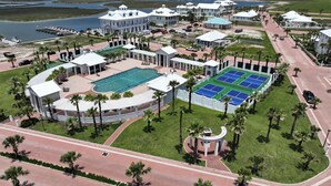 Luftaufnahme eines Resorts mit großem Swimmingpool, Tennisplätzen und einer Marina.
