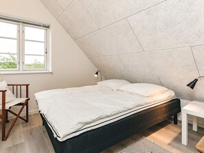 Un dormitorio con cama, escritorio y silla.