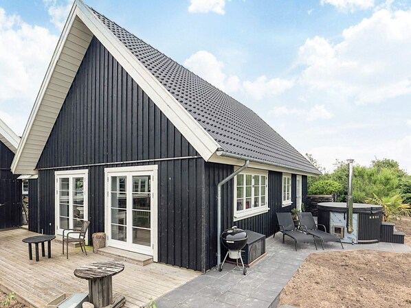 A black house with a sloped roof, white-framed windows, and a patio area with outdoor furniture. - 4 Star Holiday Home in Ranum (Ranum)