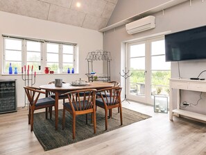 A dining area with a round table, chairs, and a rug. There is a television on a stand to the right.