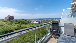 Een balkon met uitzicht op een kustlandschap, inclusief huizen en een weg.