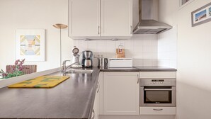 Een moderne keuken met witte kastjes, een roestvrijstalen aanrecht, een koffiezetapparaat, een broodrooster en een oven.