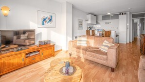 Een moderne woonkamer met een grote flatscreen televisie, een houten tv-meubel en een beige bank.