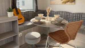 A cozy dining area with a round table, a wicker chair, and a guitar leaning against a wall. - RBR 433 - Beach Resort Kamperland (Kamperland)