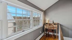 A room with a large window, a desk with a chair, and a lamp. - Historic Mill House near the Covered Bridge (Quechee)