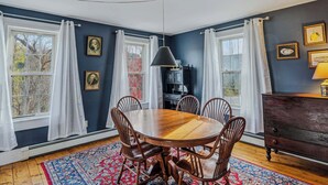 A dining room with a wooden table and chairs, a chandelier, and a fireplace. - Historic Mill House near the Covered Bridge (Quechee)