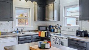 A kitchen with dark cabinets, a microwave, a stove, and a toaster. - Historic Mill House near the Covered Bridge (Quechee)