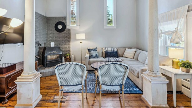 A living room with a fireplace, a sofa set, two wicker chairs, a coffee table, and a TV. - Historic Mill House near the Covered Bridge (Quechee)