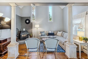 A living room with a fireplace, a sofa set, two wicker chairs, a coffee table, and a TV. - Historic Mill House near the Covered Bridge (Quechee)