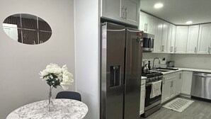 A modern kitchen with a built-in refrigerator, oven, and microwave. There is a dining table with chairs and a vase of flowers.