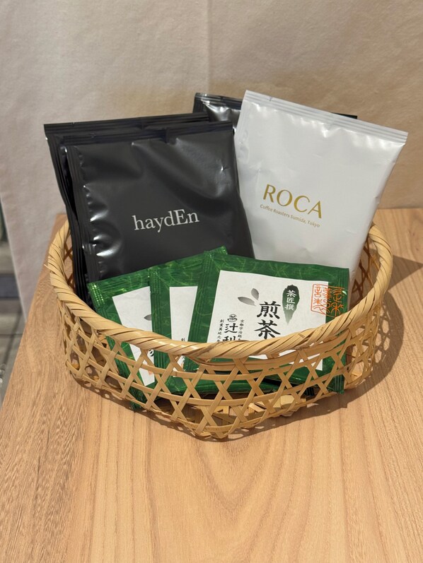 A woven basket containing coffee bags from Roca and haydEn, with a wooden surface beneath.
