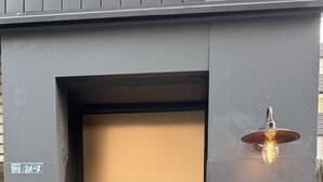 A modern building entrance with a metallic door, a small wooden sign, and a light fixture above the door. - Walking distance from Asakusa｜ Moon presentation only in January and February｜ Rice cooking and sake｜ Private use of one floor｜ Couple/Family｜ 36 square meters｜ Max. 4 persons (Matsugaya, Taito City)