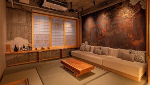 A traditional Japanese-style living room with tatami flooring, a low wooden coffee table, a sofa with cushions, and a shoji screen window. - Walking distance from Asakusa｜ Moon presentation only in January and February｜ Rice cooking and sake｜ Private use of one floor｜ Couple/Family｜ 36 square meters｜ Max. 4 persons (Matsugaya, Taito City)