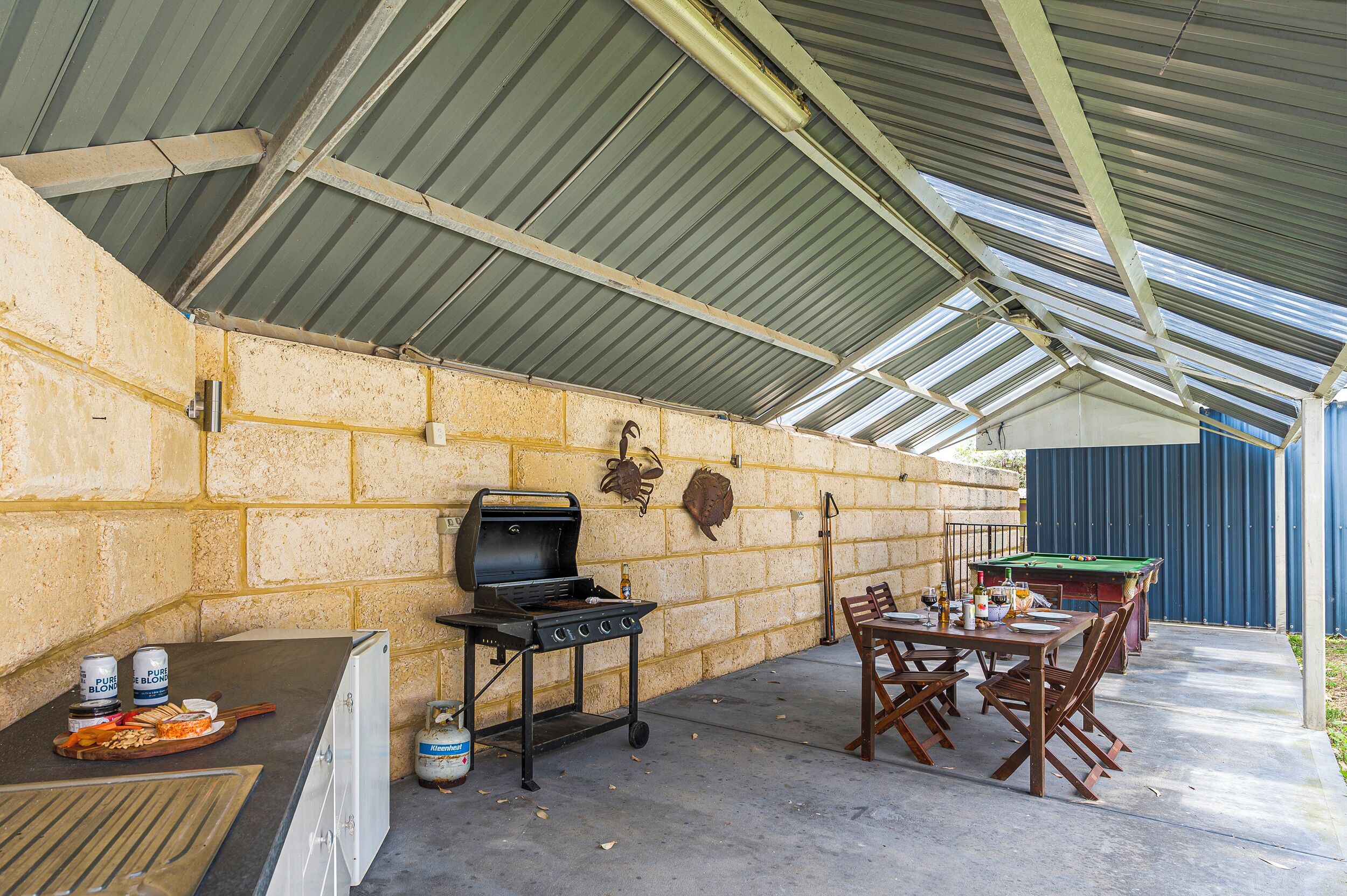 An outdoor patio with a barbecue grill, a pool table, and a dining table with chairs.