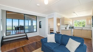 Un salon moderne avec un canapé bleu, un coin repas avec une table et des chaises, et une cuisine équipée de placards et d’un four à micro-ondes.