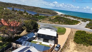 Une maison moderne dotée de panneaux solaires, d’une allée et offrant une vue sur la mer et les collines.