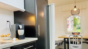 Une cuisine moderne avec des meubles de couleur noire, une machine à café et un bol d’oranges posé sur le comptoir.