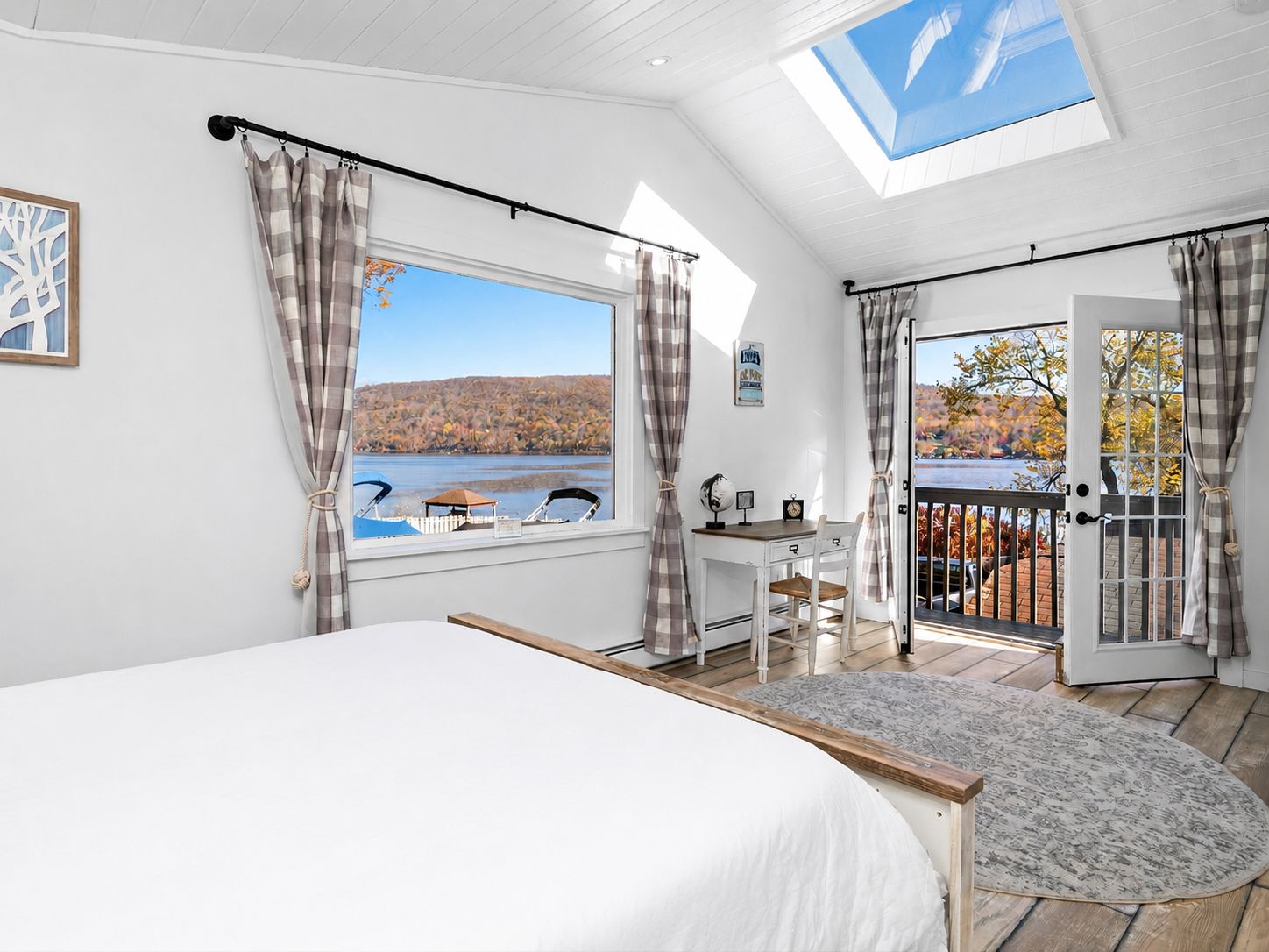 A bedroom with a large bed, a desk, and a view of a lake.