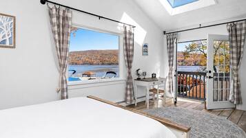A bedroom with a large bed, a desk, and a view of a lake.