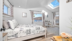Une chambre avec un lit, un bureau et une vue sur un lac.