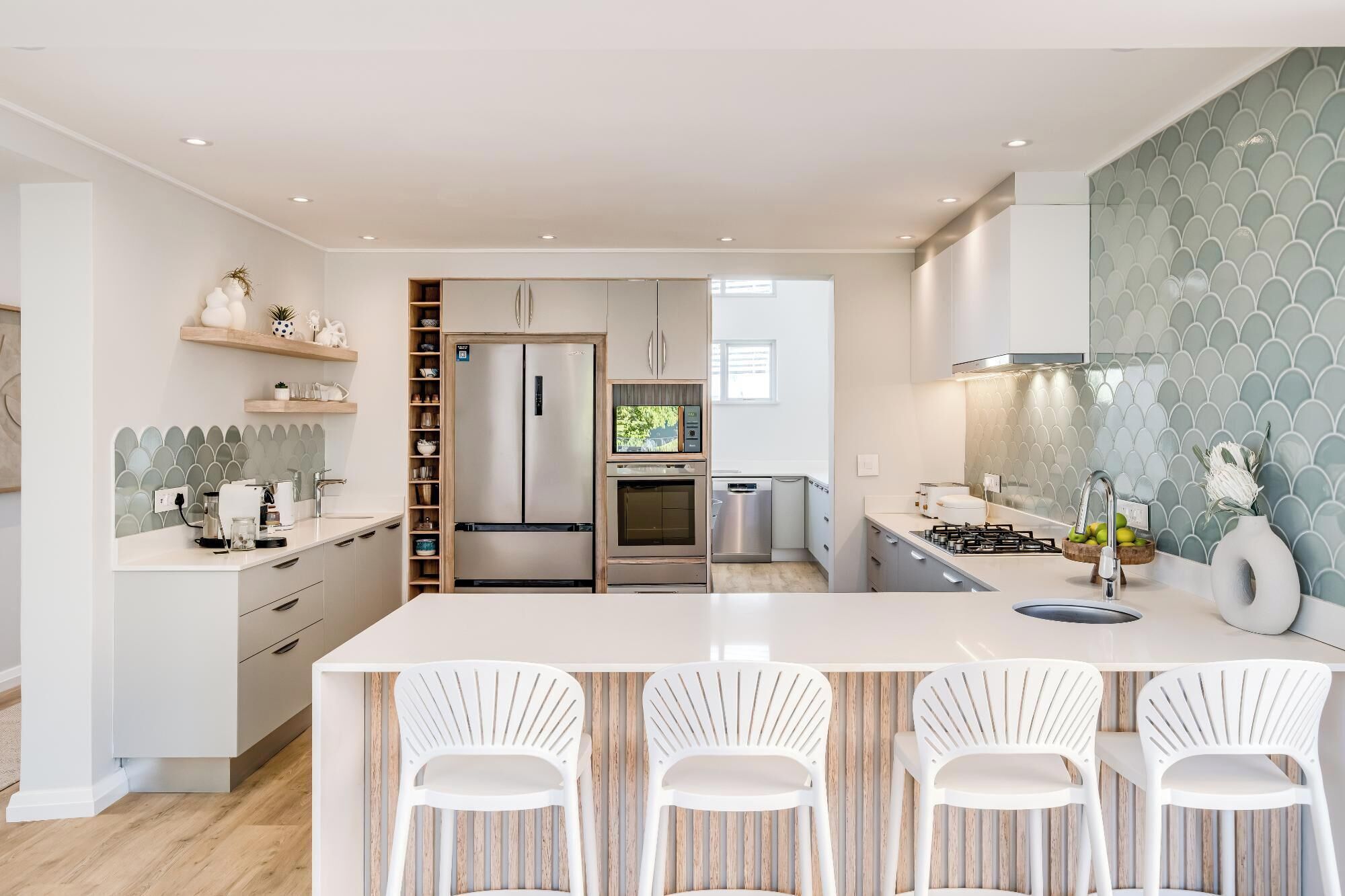 A modern kitchen with a central island, built-in appliances, and a decorative backsplash.