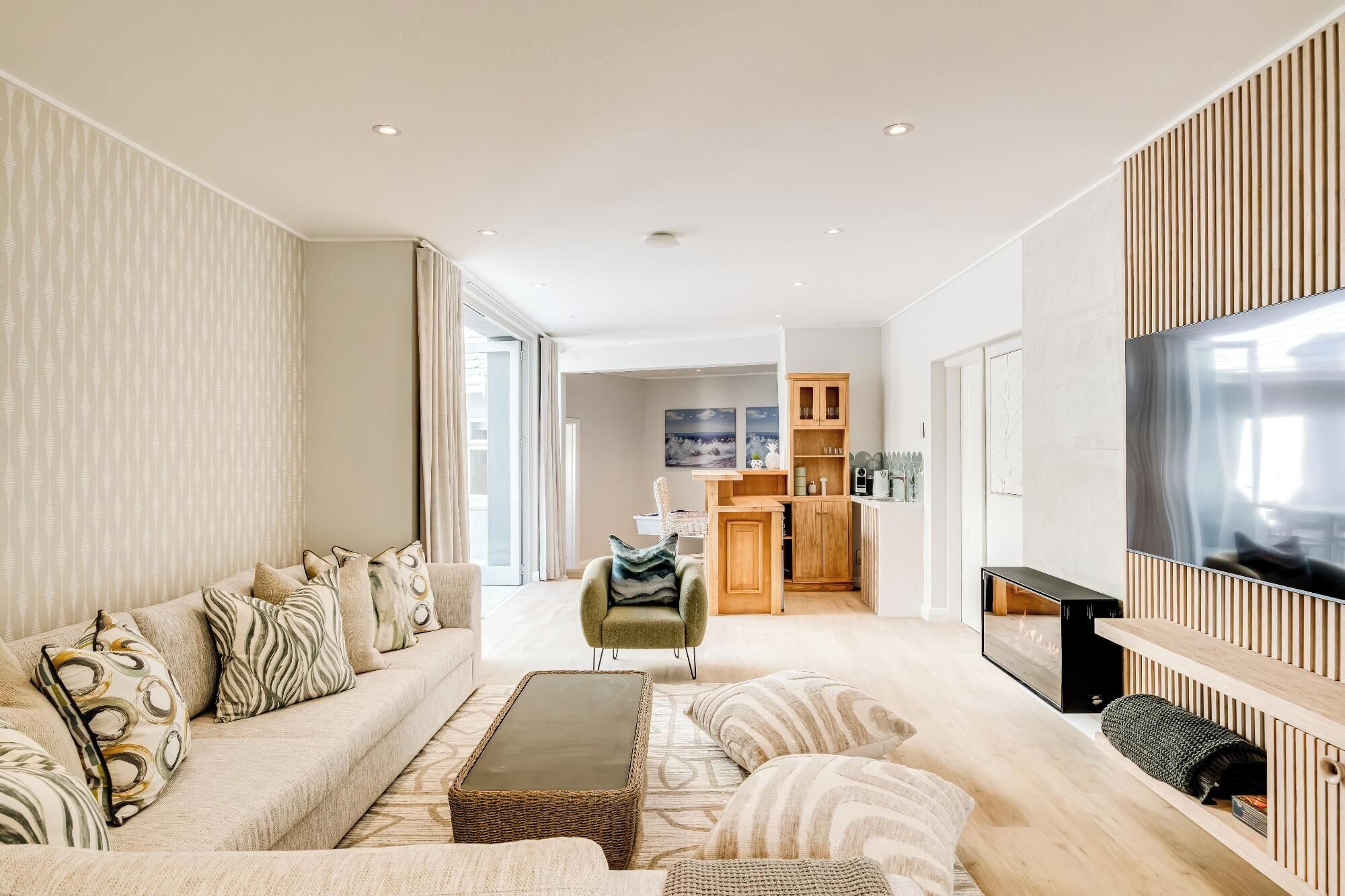 A modern living room with a sofa, coffee table, and a TV mounted on the wall.