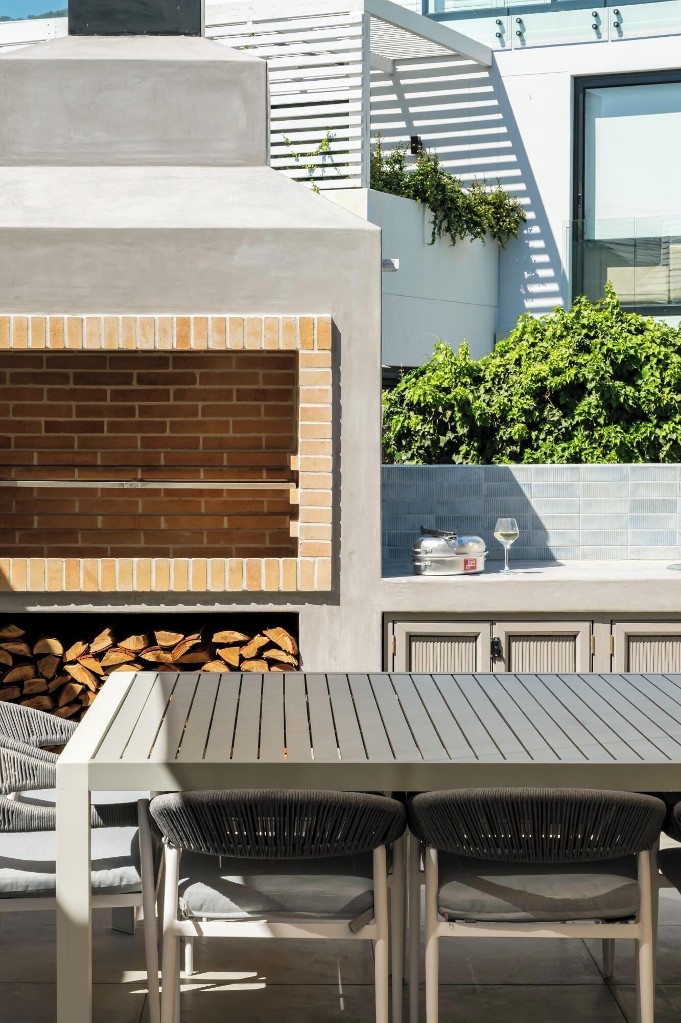 An outdoor patio with a brick fireplace, a grill, and a seating area with chairs.