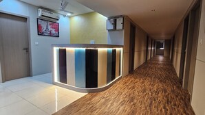 Un pasillo de hotel con mostrador de recepción, unidades de aire acondicionado y suelo de madera.