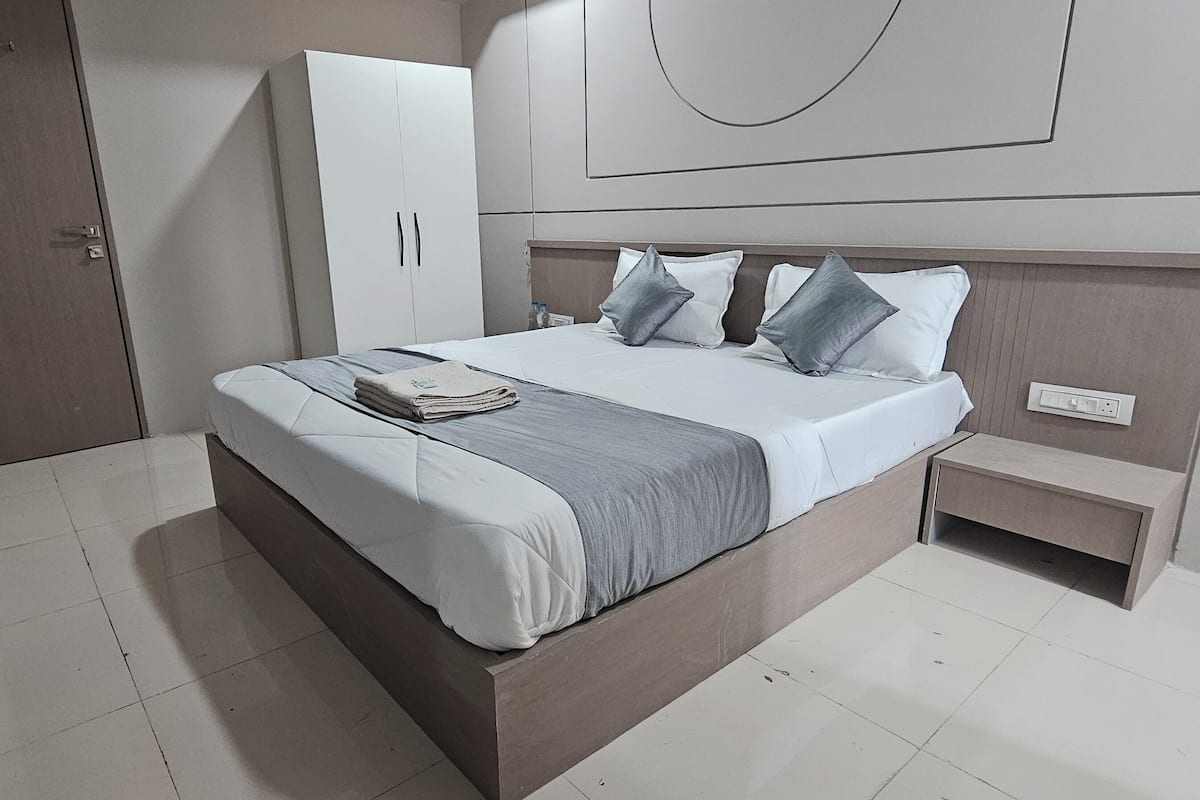 Een moderne hotelkamer met een groot bed, een nachtkastje en een kledingkast.