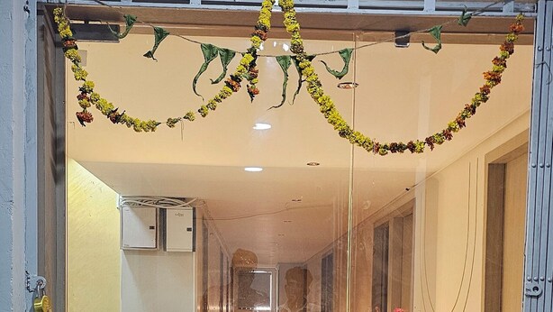 Zona de recepción de hotel con suelo de madera, un mostrador de recepción y puerta de entrada de cristal.