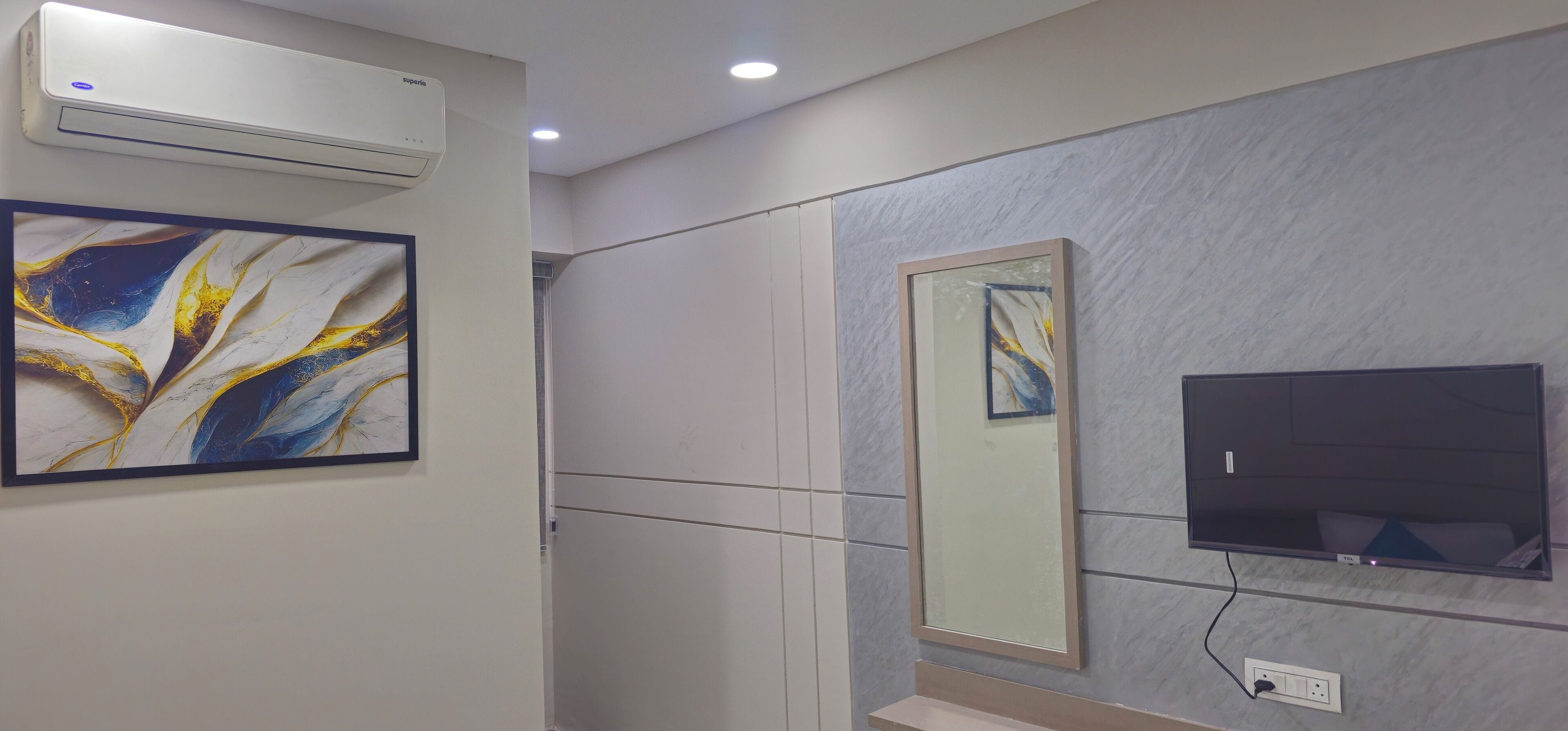 A modern bathroom with a large mirror, a flat-screen TV, and an air conditioning unit.